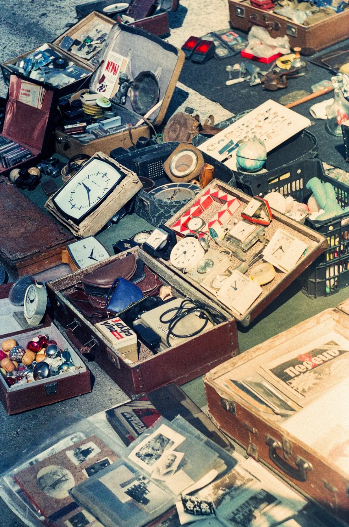A flea market table covered in vintage objects, clocks, suitcases and trinkets